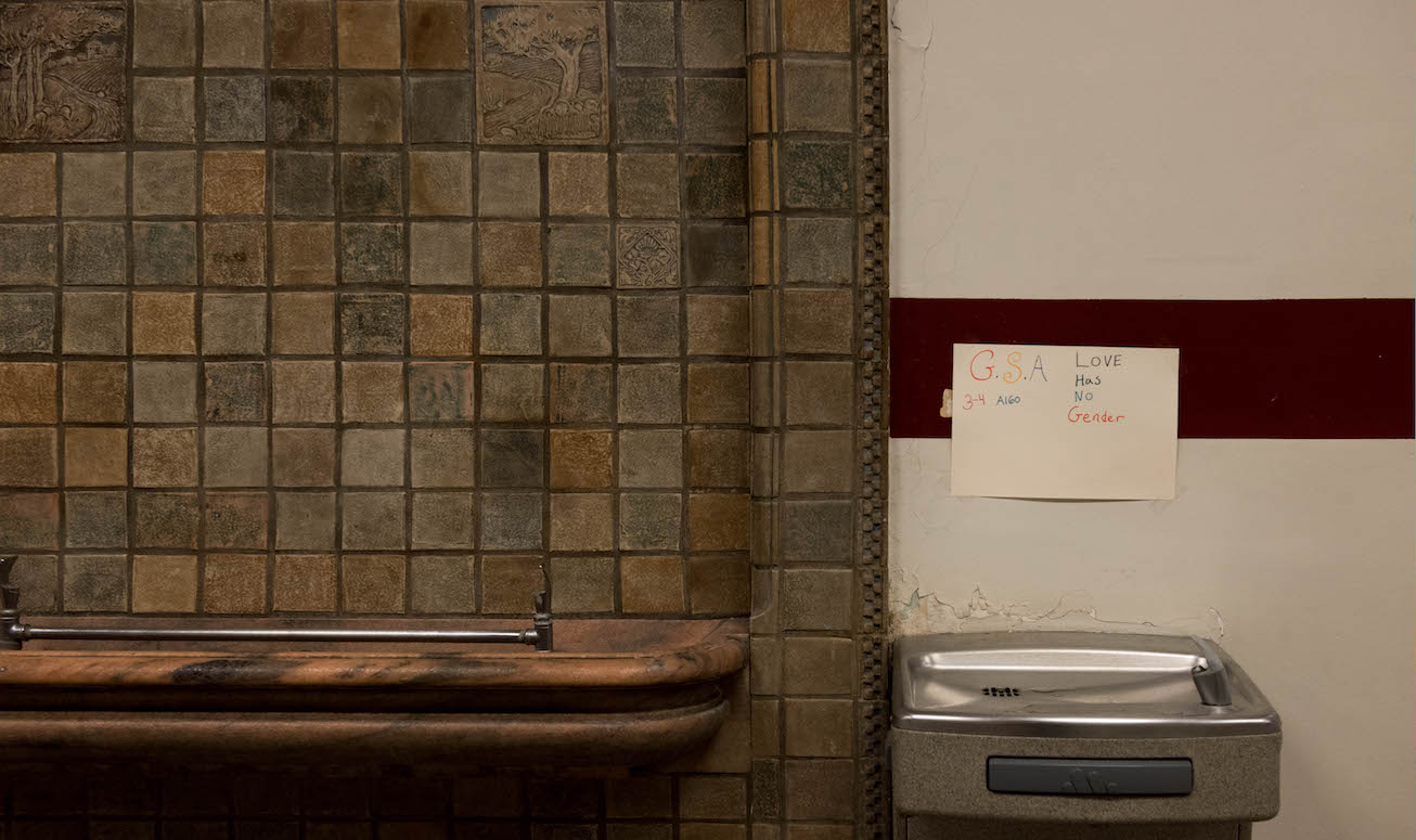 Plaster cracks around the wall-mounted base of a water fountain at Muskegon High.