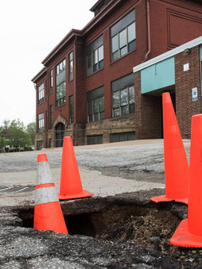 Gaping sinkholes such as this one outside the J Building of Muskegon High constitute the sort of overlooked capital repairs that many tax-poor districts cannot afford to make.
