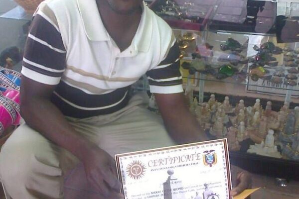 Ansly Damus kneels in a store holding a certificate