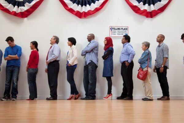 a line of people stand in line waiting to vote