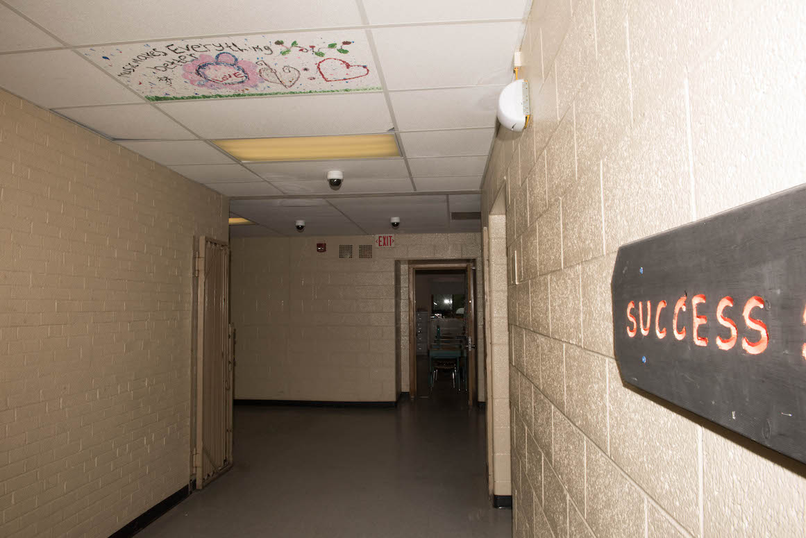 As an art activity, students paint the particle board on the ceiling to conceal the brown water stains left by the school's leaking roof.