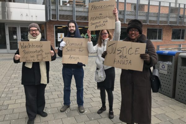 Supporters of Anuja Rajendra stand outside court with signs