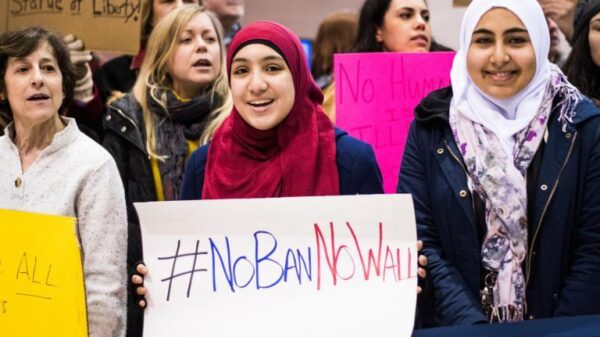 woman wearing hijab holds sign that says "No Ban, No Wall"