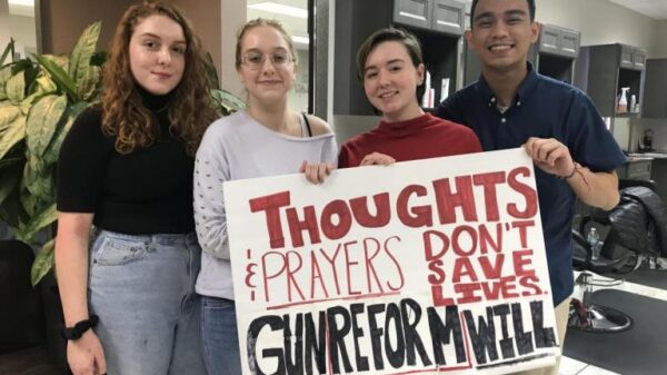 Students holding sign reading "Thoughts and prayers don't save lives, gun reform will"