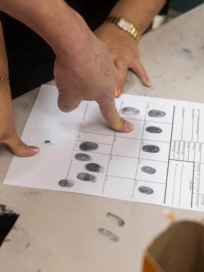 People inking their fingers for fingerprints on a paper.
