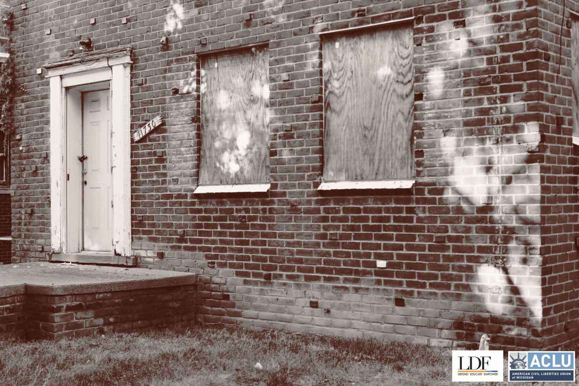 A foreclosed house with boarded up windows.