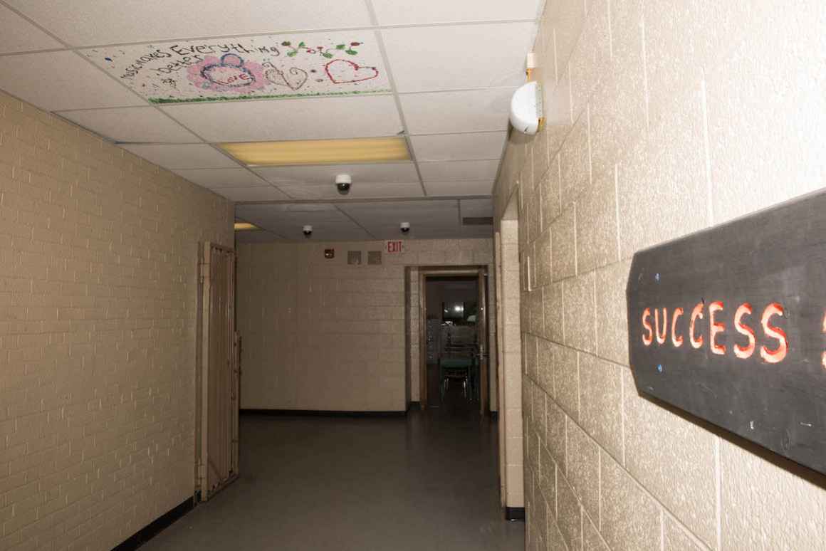  As an art activity, students paint the particle board on the ceiling to conceal the brown water stains left by the school's leaking roof.