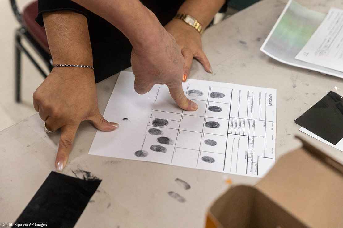 People inking their fingers for fingerprints on a paper.