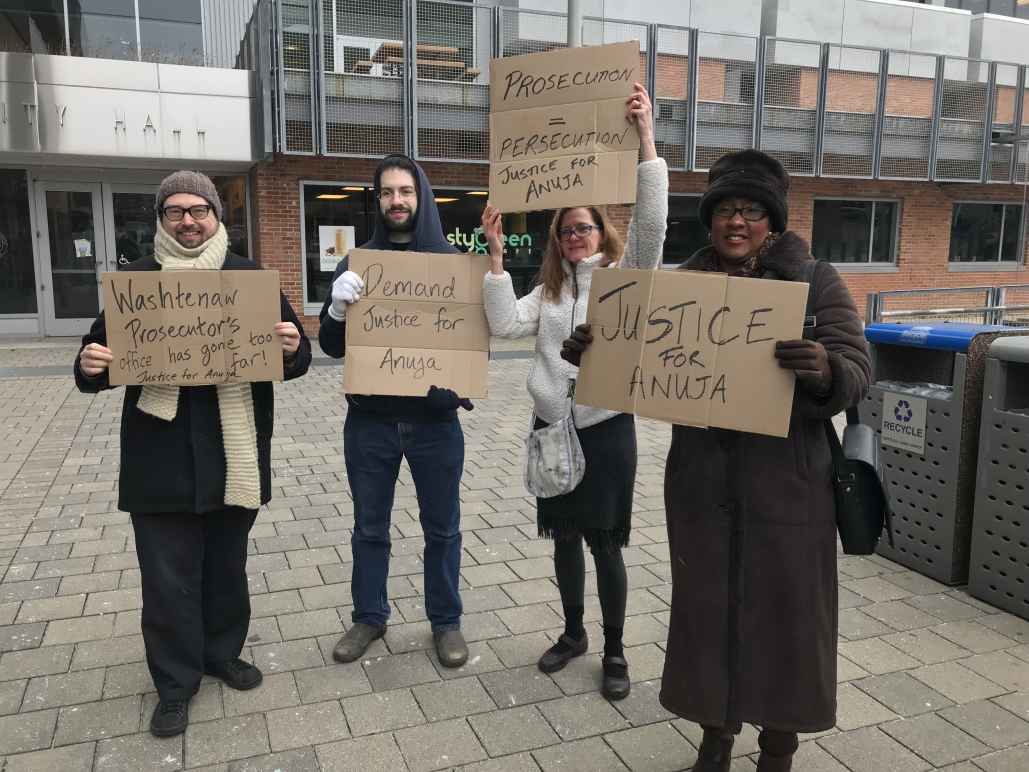 Supporters of Anuja Rajendra stand outside court with signs