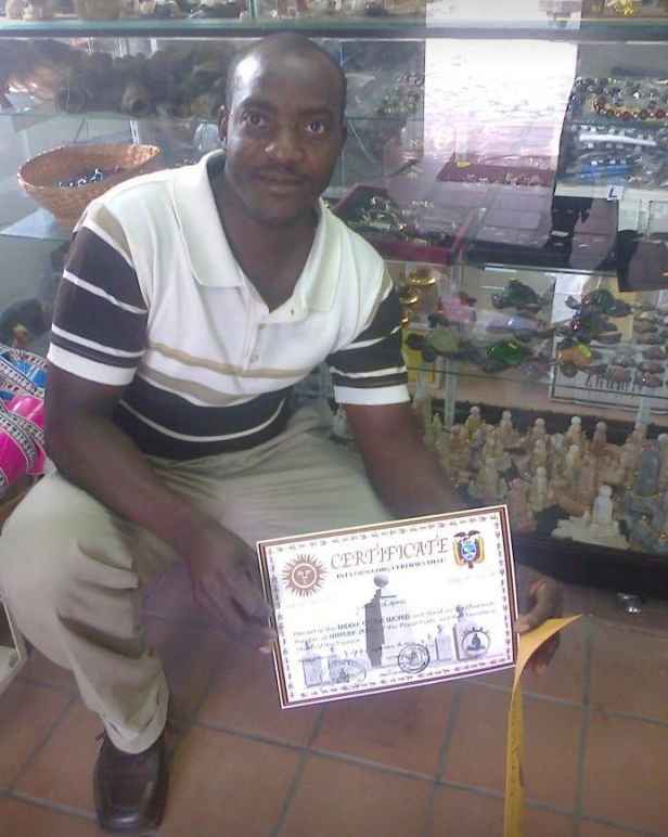 Ansly Damus kneels in a store holding a certificate