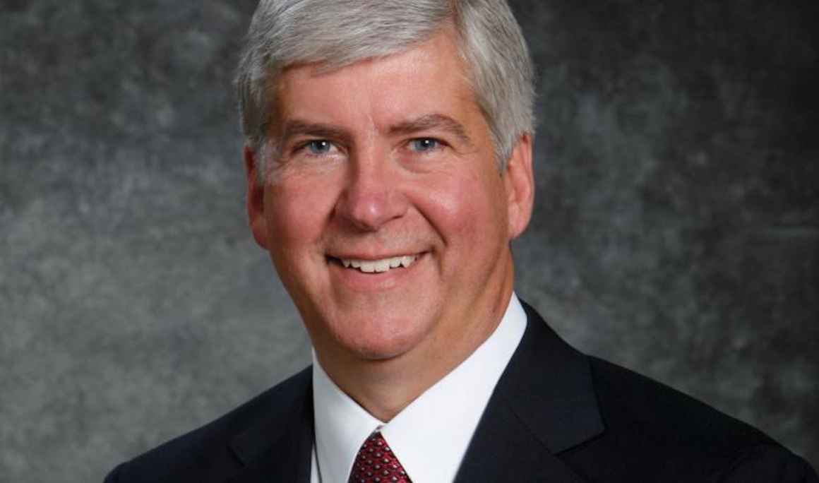 A headshot of Governor Snyder. He has a big smile on his face, salt and pepper closely cropped hair and a suit with a red tie. 