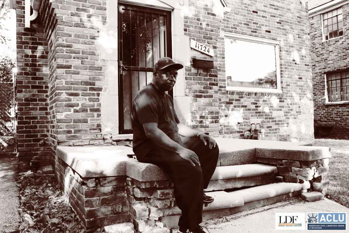 Walter Hicks sits on his home's stopp. He looks at the camera with his hands on his knees, one foot propped on a step.