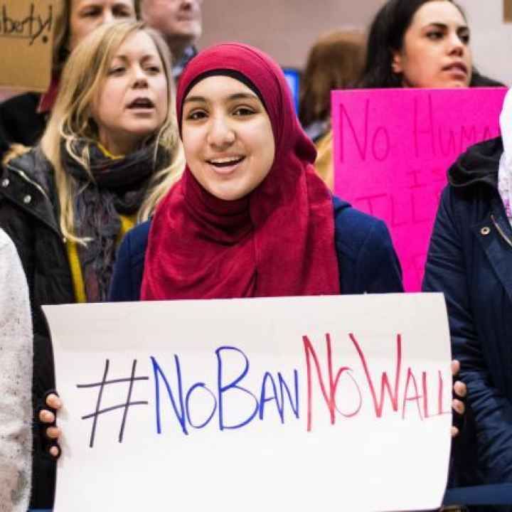 woman wearing hijab holds sign that says "No Ban, No Wall"