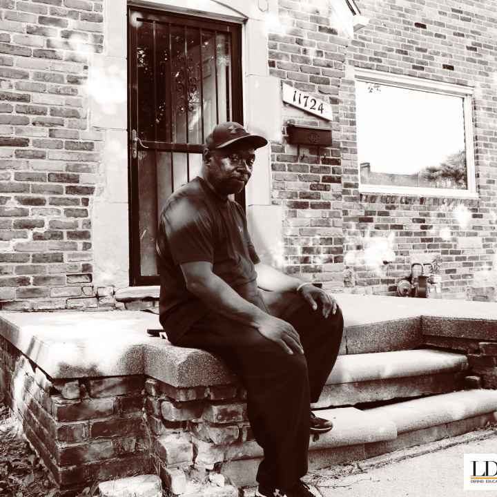 Walter Hicks Walter Hicks sits on his home's stopp. He looks at the camera with his hands on his knees, one foot propped on a step.